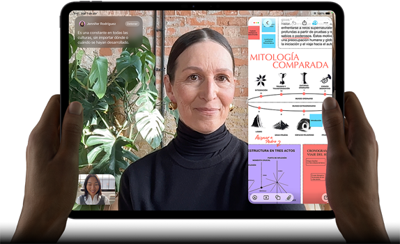 iPad Pro, parte frontal, posición horizontal, negro espacial, esquinas redondeadas, marco de la pantalla negro, manos sosteniendo los lados izquierdo y derecho, la pantalla muestra una conversación en FaceTime que se está traduciendo en vivo, y una app educativa que muestra una presentación sobre 