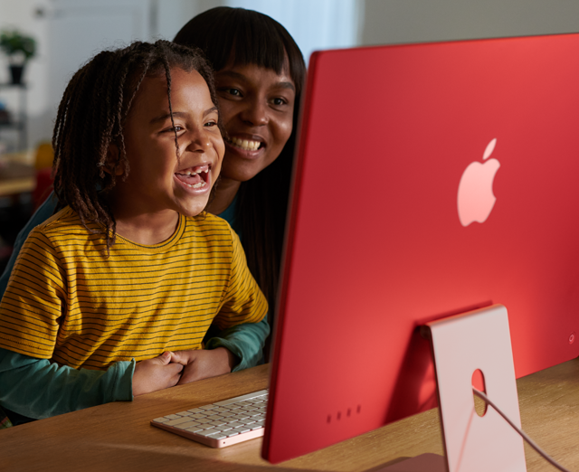 Una familia riéndose mientras mira un programa en la iMac.